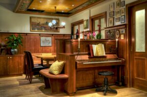 Restaurant room with wooden walls, piano, and neatly set tables
