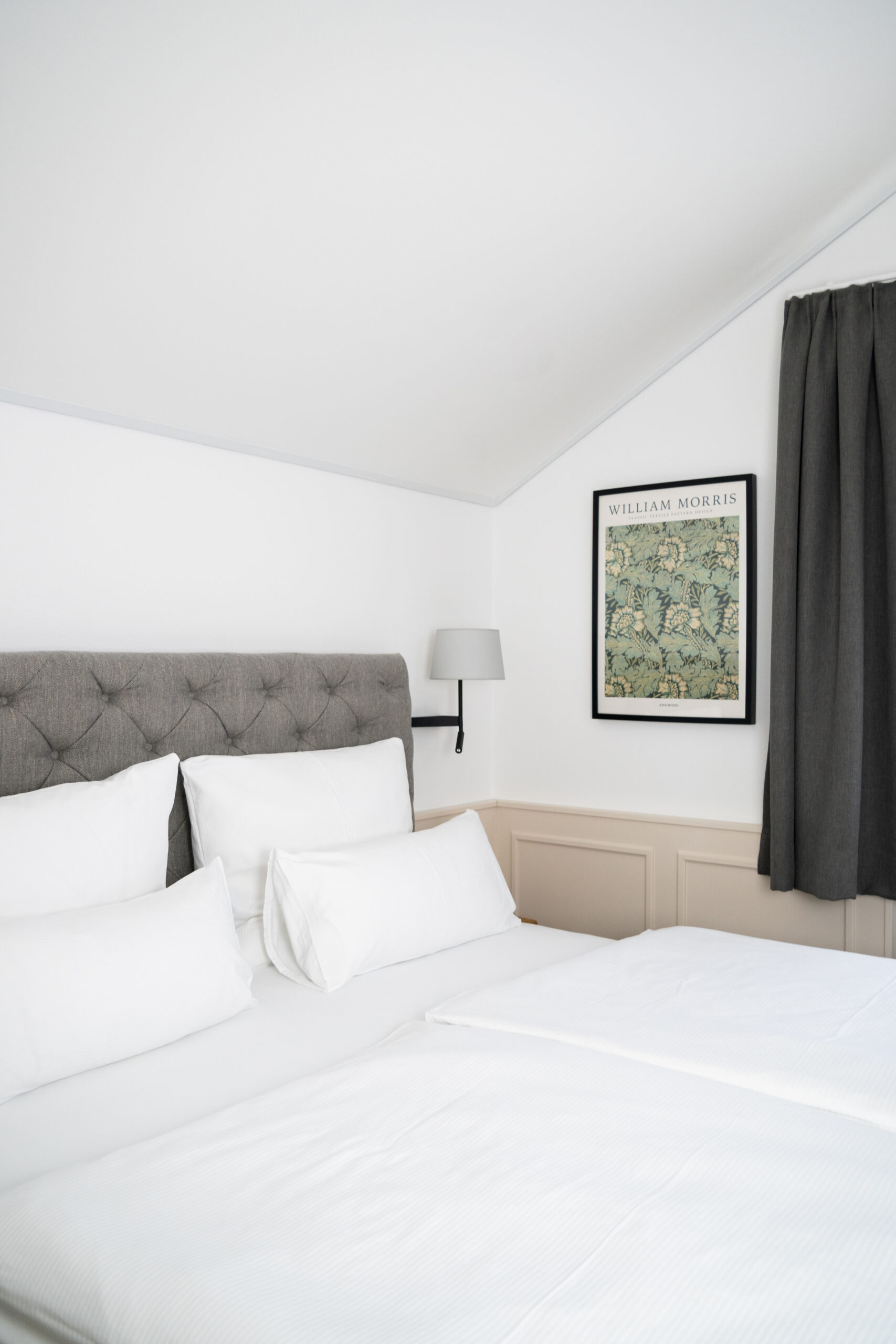 Elegant hotel room with sloped ceiling and framed artwork
