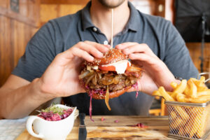 Gourmet burger with hands holding the bun and fries on the side
