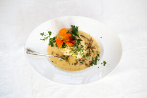 Clear soup with vegetables and herbs in a white bowl

