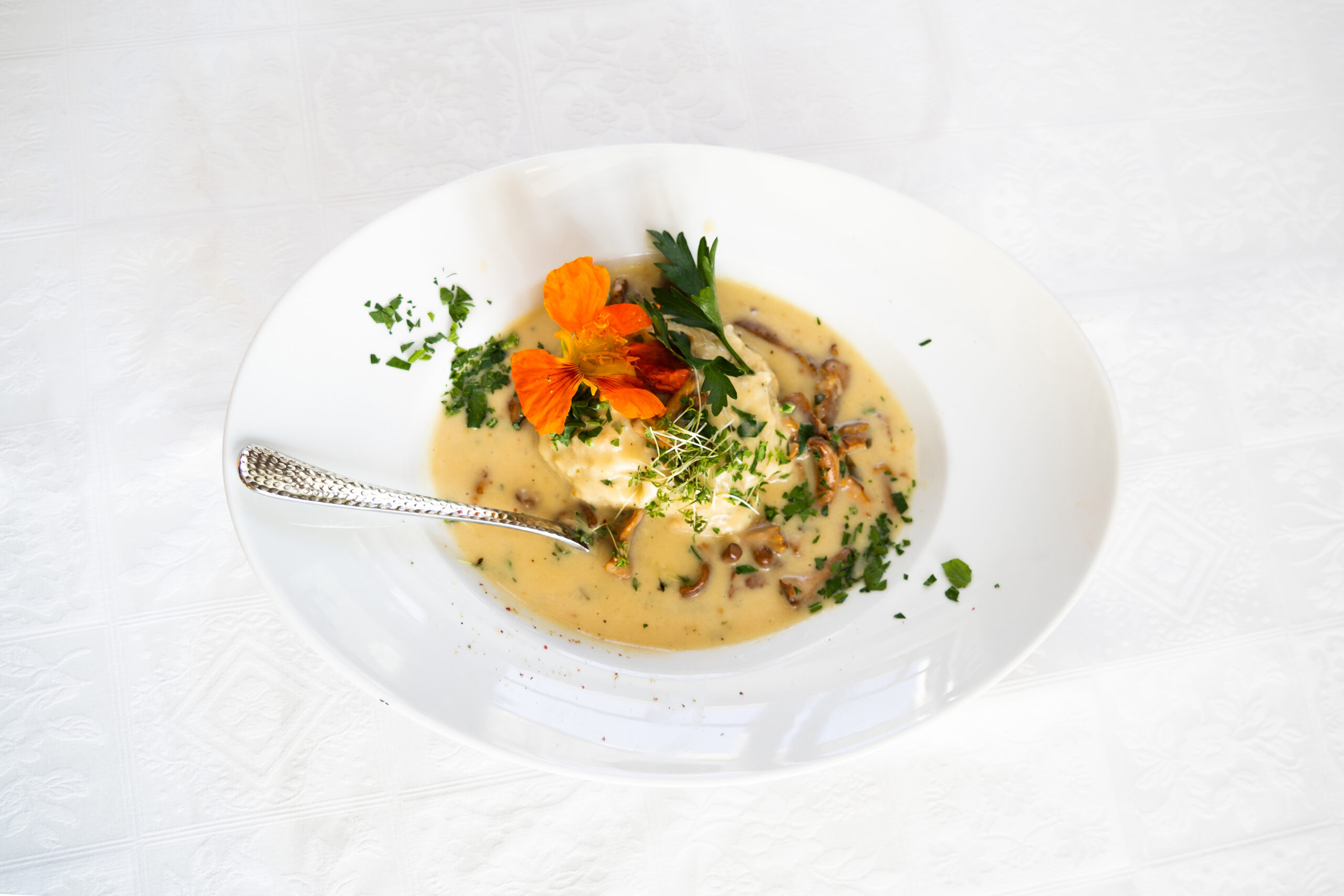 Clear soup with vegetables and herbs in a white bowl
