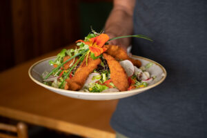 Plate of fried fish served with potatoes and fresh herbs
