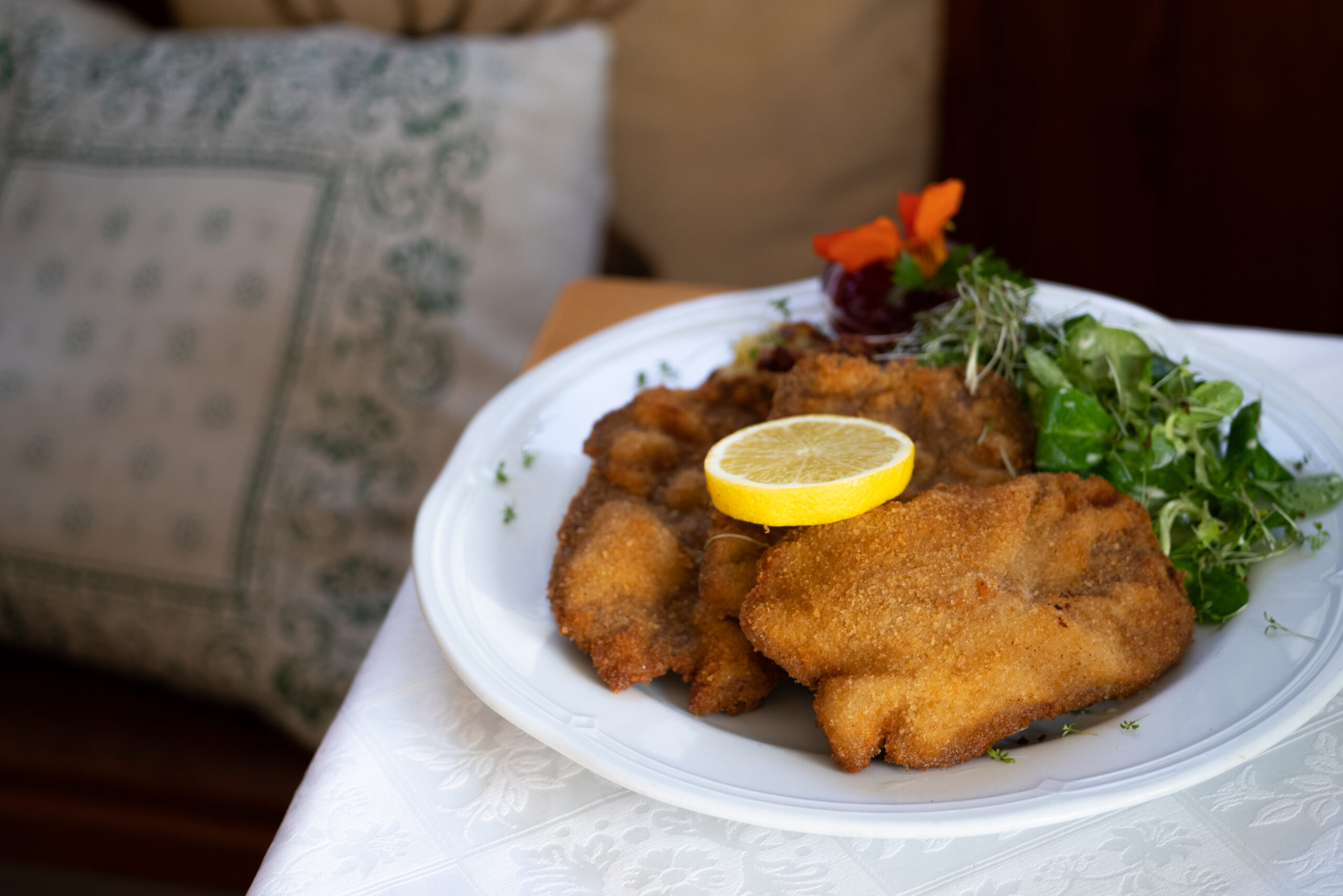 Knuspriges Wiener Schnitzel mit Zitronenscheibe auf einem Teller.