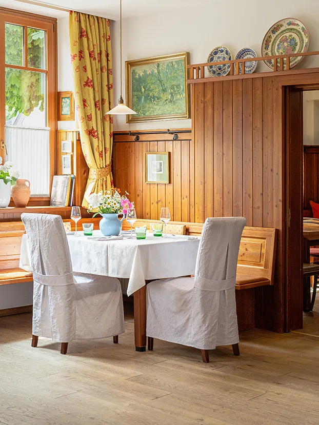 Gemütlich gedeckter Restauranttisch mit Blumen und natürlichem Tageslicht.