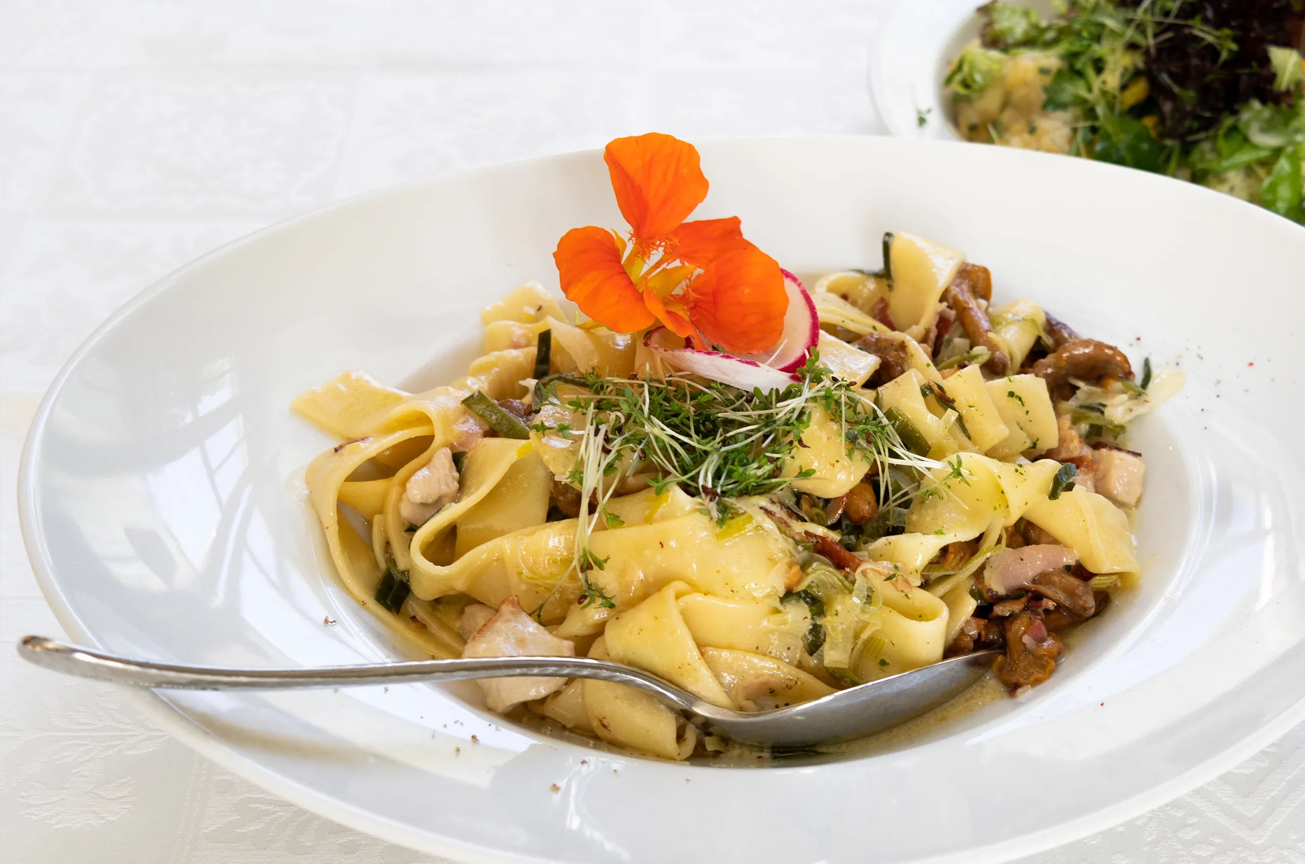 Bandnudeln mit frischem Gemüse, Kräutern und essbaren Blüten.