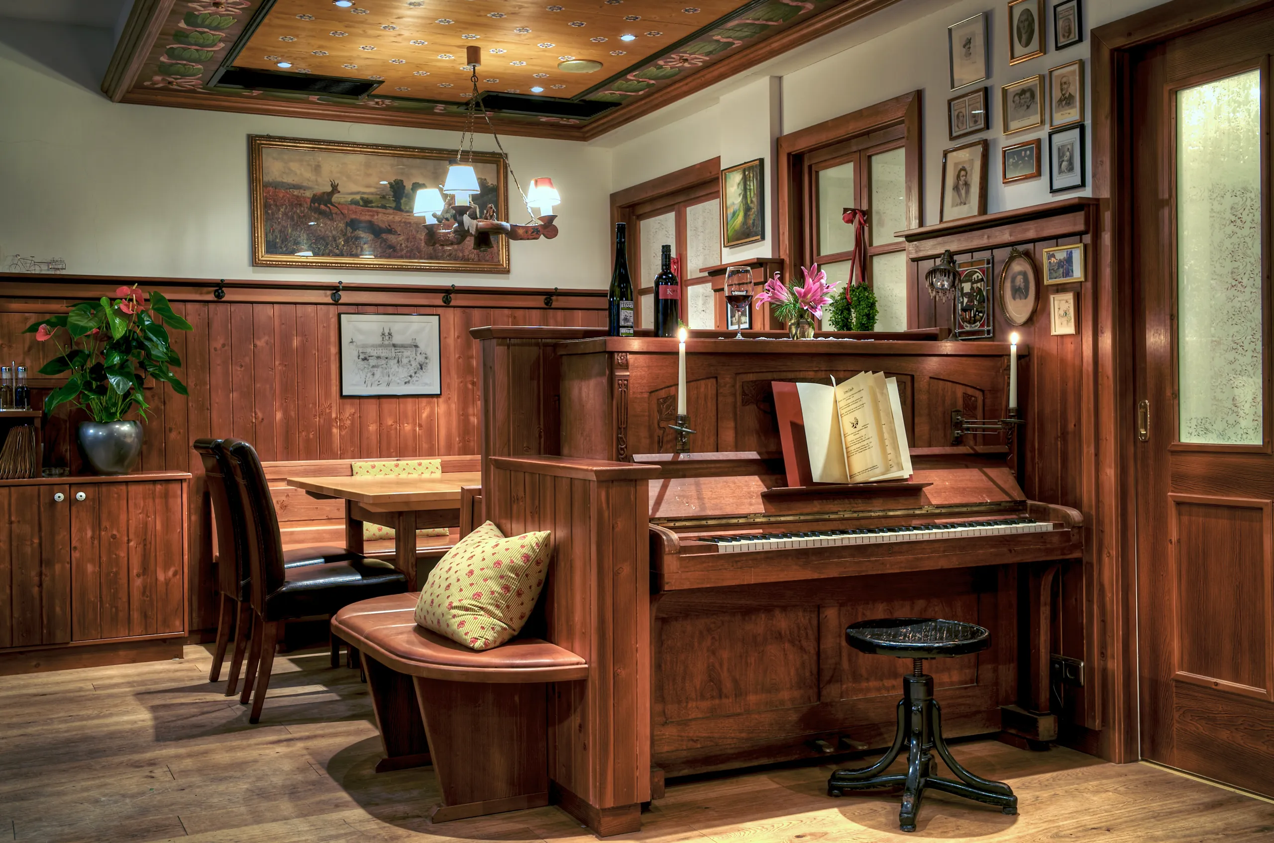 Gemütliches Gaststüberl mit Holzwänden, Klavier, Kerzenlicht und einem einladend gedeckten Tisch.