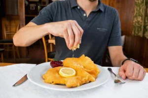 Guest squeezing lemon over a freshly fried schnitzel
