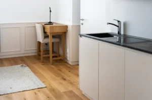 Compact kitchenette area with wooden flooring and a high seating table
